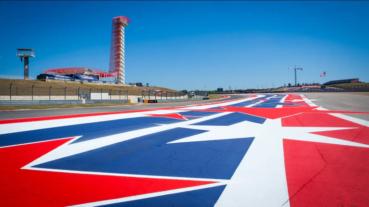 Quattro moto MotoGP in pista a Circuit of The Americas con le tribune dello stadio sullo sfondo